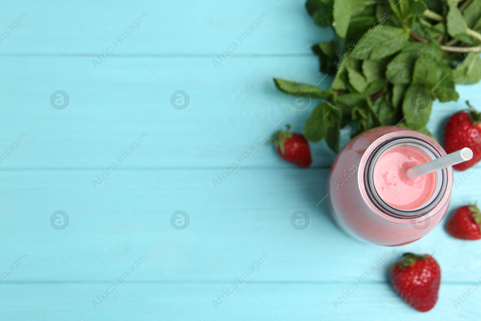 Photo of Tasty strawberry smoothie and mint on light blue wooden table, flat lay. Space for text