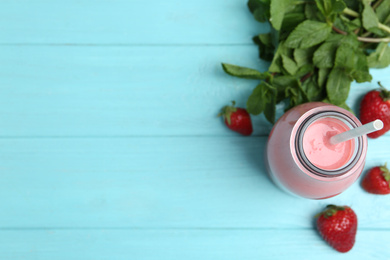 Photo of Tasty strawberry smoothie and mint on light blue wooden table, flat lay. Space for text