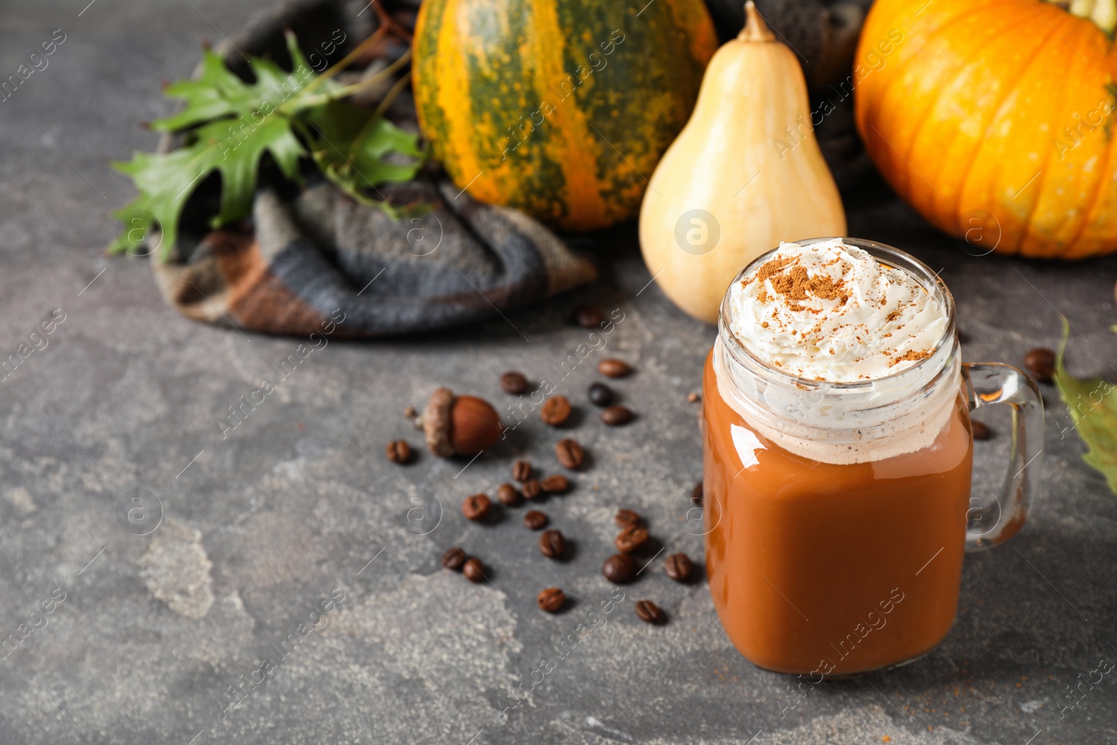 Photo of Mason jar with tasty pumpkin spice latte on grey table. Space for text
