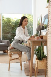 Young woman working at table in light room. Home office