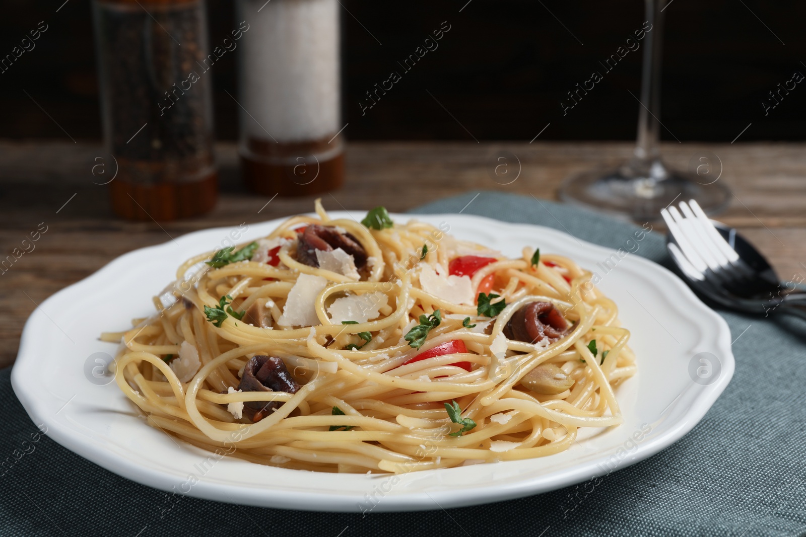 Photo of Delicious pasta with anchovies, tomatoes and parmesan cheese on table, closeup