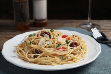 Delicious pasta with anchovies, tomatoes and parmesan cheese on table, closeup