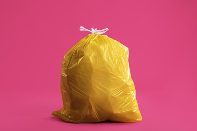 Trash bag full of garbage on pink background