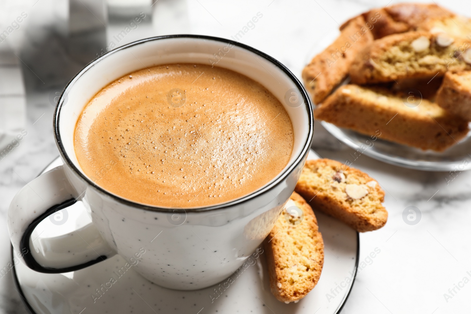 Photo of Tasty cantucci and cup of aromatic coffee on white table, closeup. Traditional Italian almond biscuits