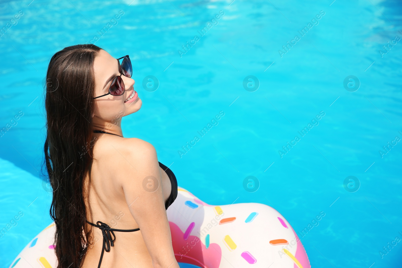 Photo of Beautiful young woman wearing bikini on inflatable ring in swimming pool