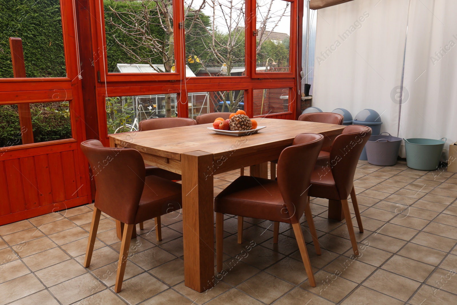 Photo of Wooden table with fruits and stylish chairs on terrace