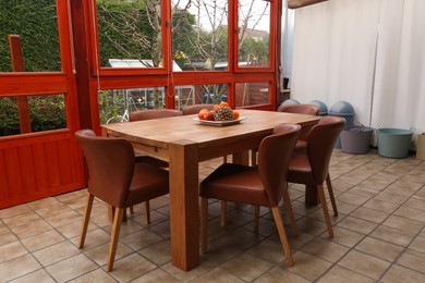 Photo of Wooden table with fruits and stylish chairs on terrace