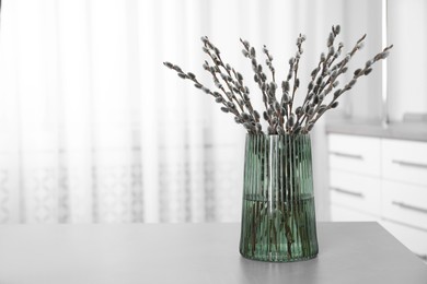 Beautiful bouquet of pussy willow branches in vase on table indoors. Space for text
