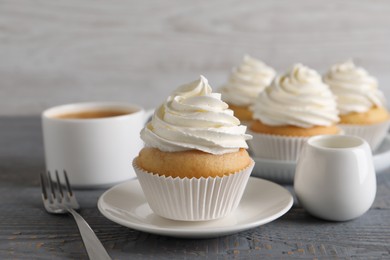 Photo of Delicious cupcake with cream on grey wooden table, closeup