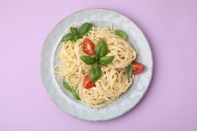 Delicious pasta with brie cheese, tomatoes and basil leaves on violet background, top view