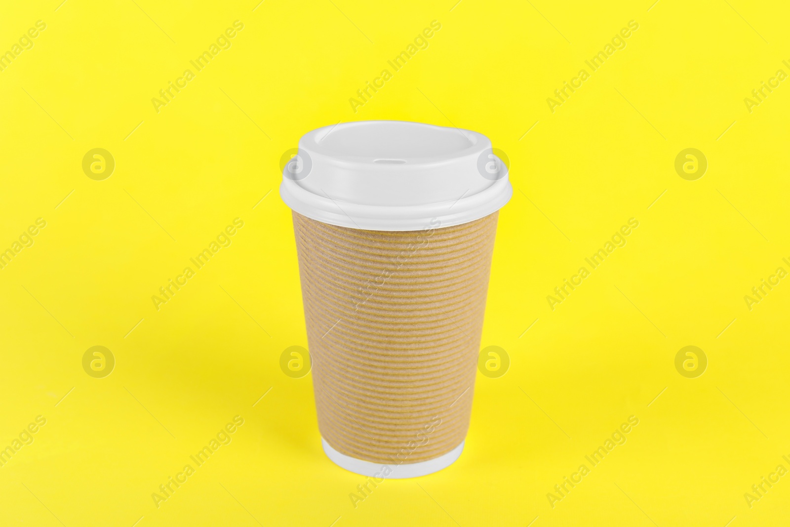 Photo of Paper cup with plastic lid on yellow background. Coffee to go