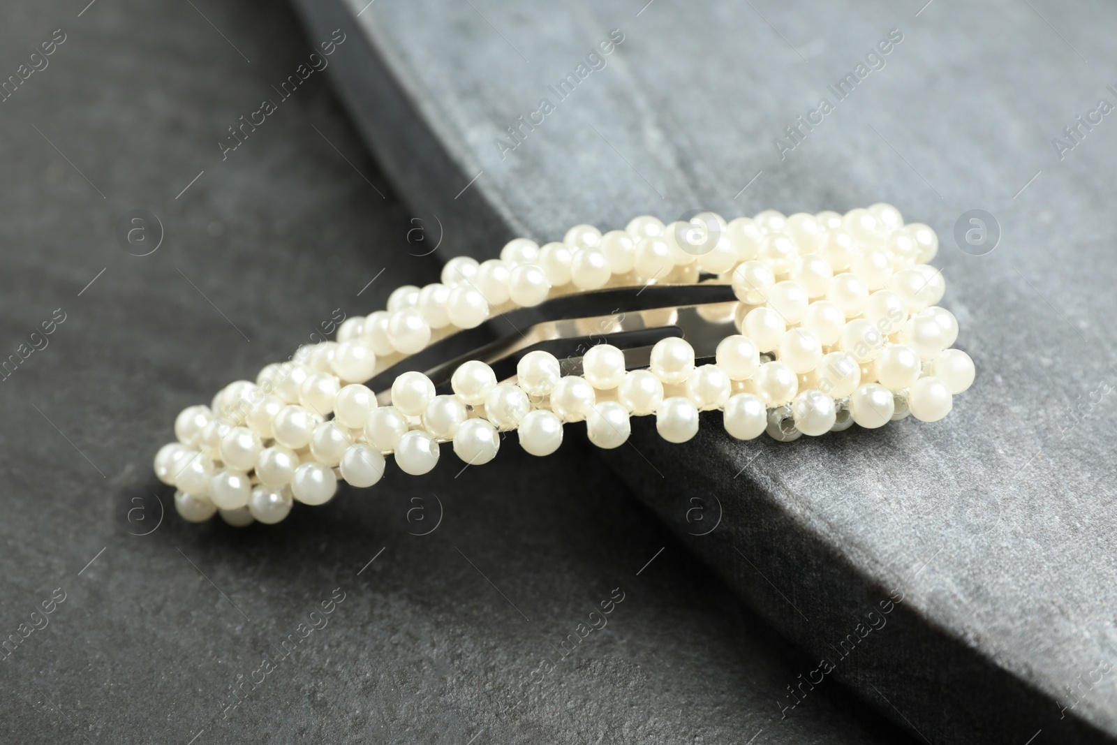 Photo of Beautiful hair clip on black stone table, closeup