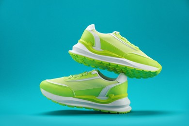 Photo of Pair of stylish green sneakers levitating on teal background