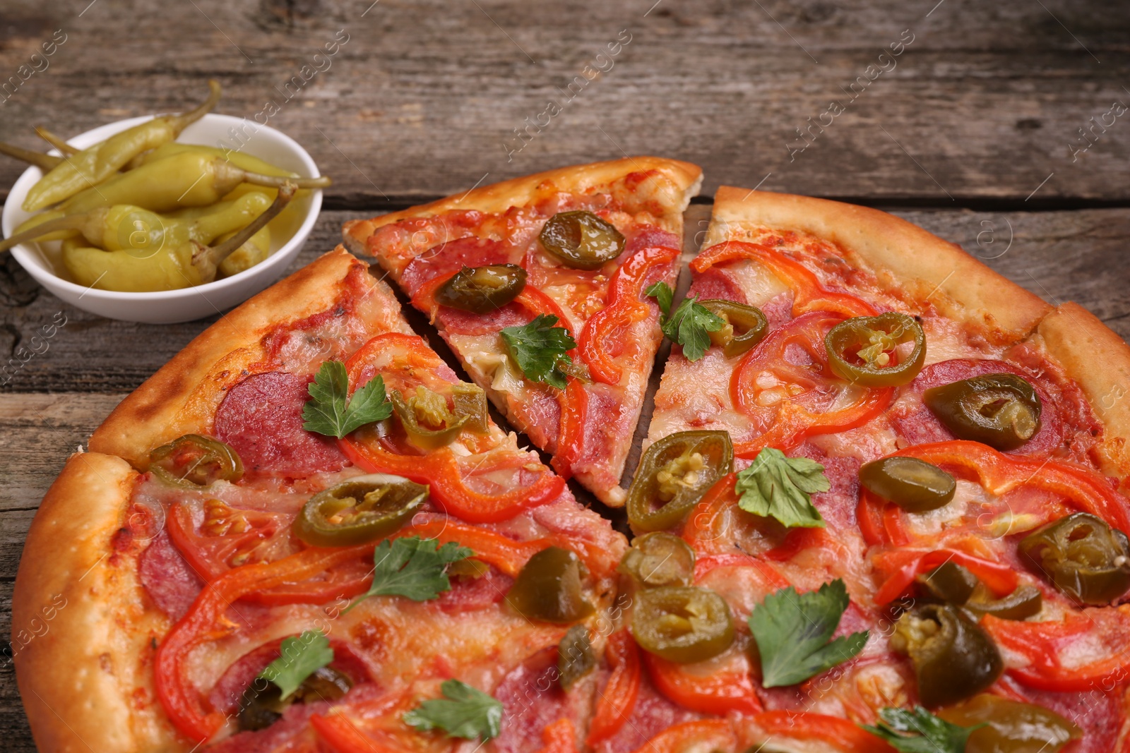 Photo of Delicious pizza Diablo and pickled peppers on wooden table, closeup