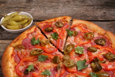 Delicious pizza Diablo and pickled peppers on wooden table, closeup