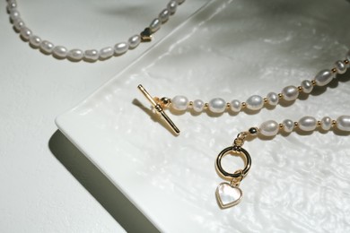 Elegant pearl necklaces on white background, closeup