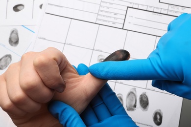 Photo of Investigator taking fingerprints of suspect at table, closeup. Criminal expertise