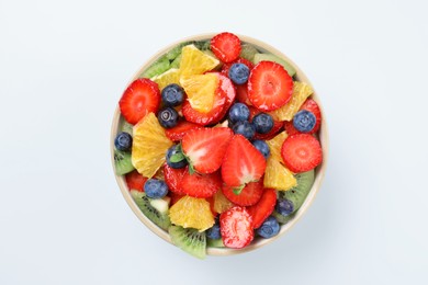 Yummy fruit salad in bowl on light blue background, top view