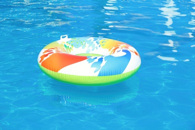 Photo of Colorful inflatable ring floating in swimming pool on sunny day
