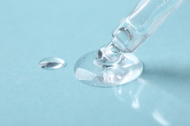 Pipette with cosmetic serum on light blue background, closeup