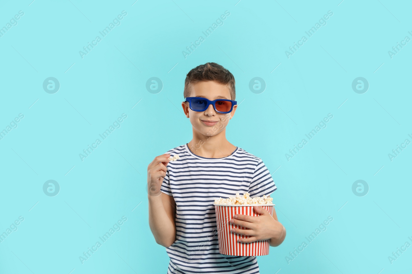 Photo of Boy with 3D glasses and popcorn during cinema show on color background