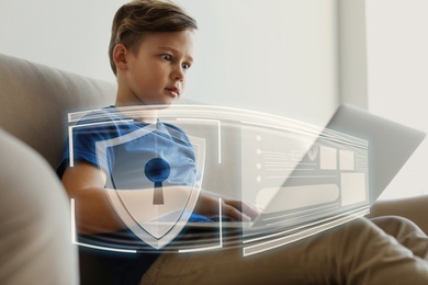 Child safety online. Emotional little boy using laptop at home. Illustration of internet blocking app on foreground
