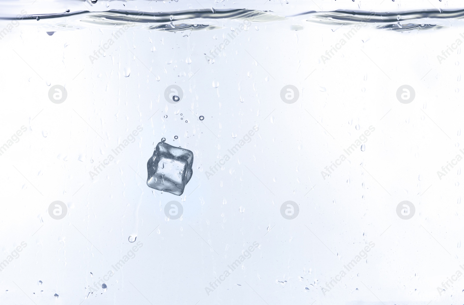 Photo of Ice cube falling into water against white background