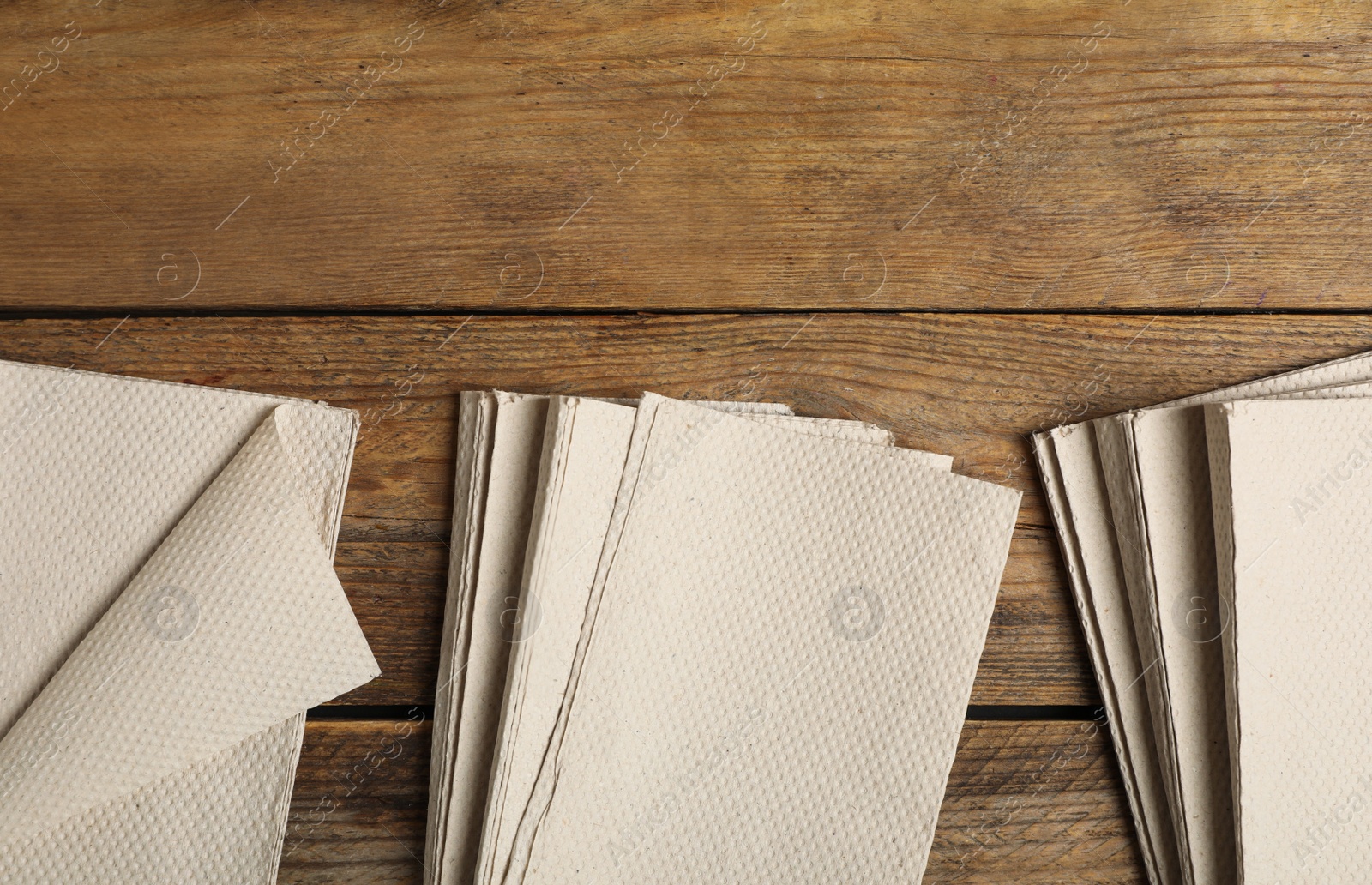 Photo of Stacks of white paper towels on wooden table, flat lay. Space for text