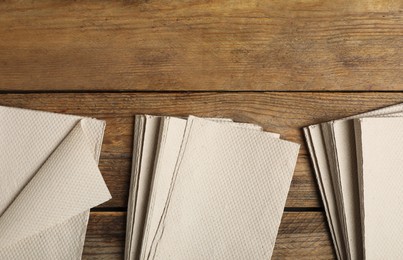 Photo of Stacks of white paper towels on wooden table, flat lay. Space for text