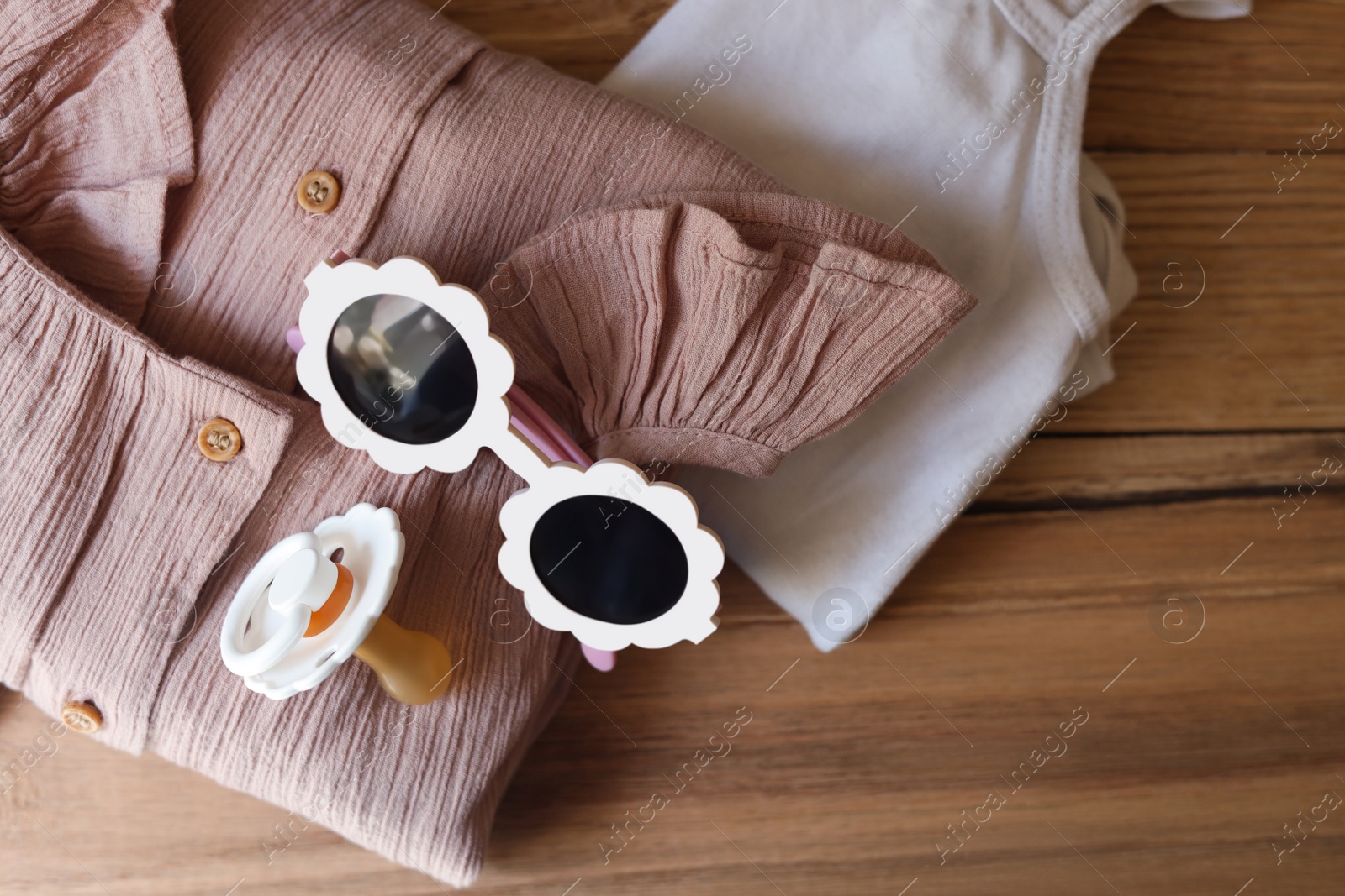 Photo of Stylish child clothes and accessories on wooden background, flat lay