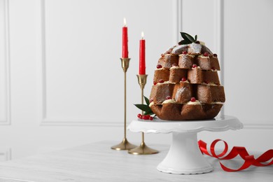 Delicious Pandoro Christmas tree cake with powdered sugar and berries near festive decor on white table. Space for text