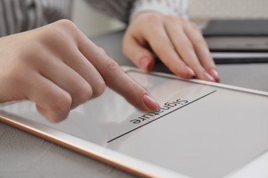 Image of Electronic signature. Woman using tablet at table, closeup