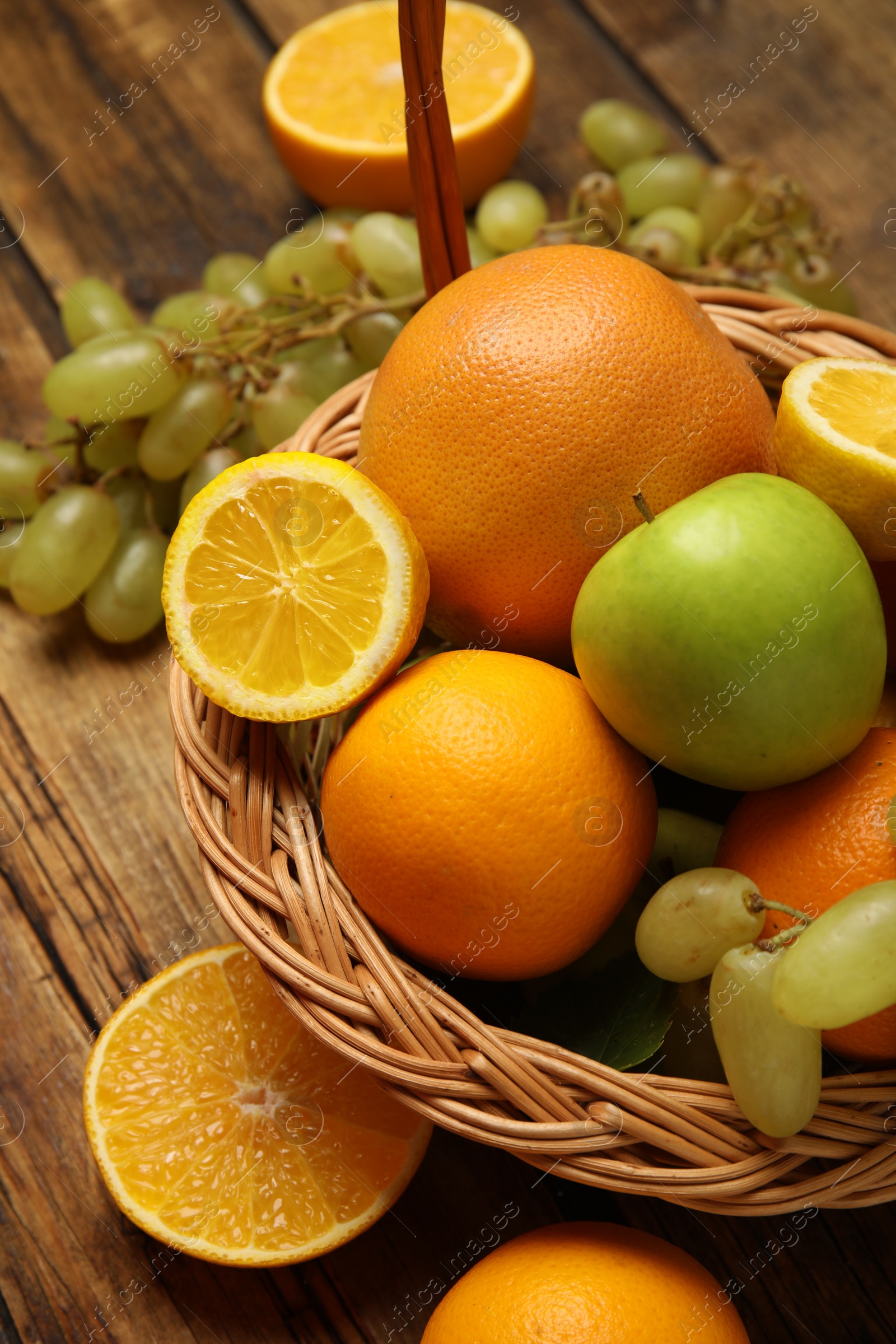 Photo of Wicker basket with different fruits on wooden table, closeup