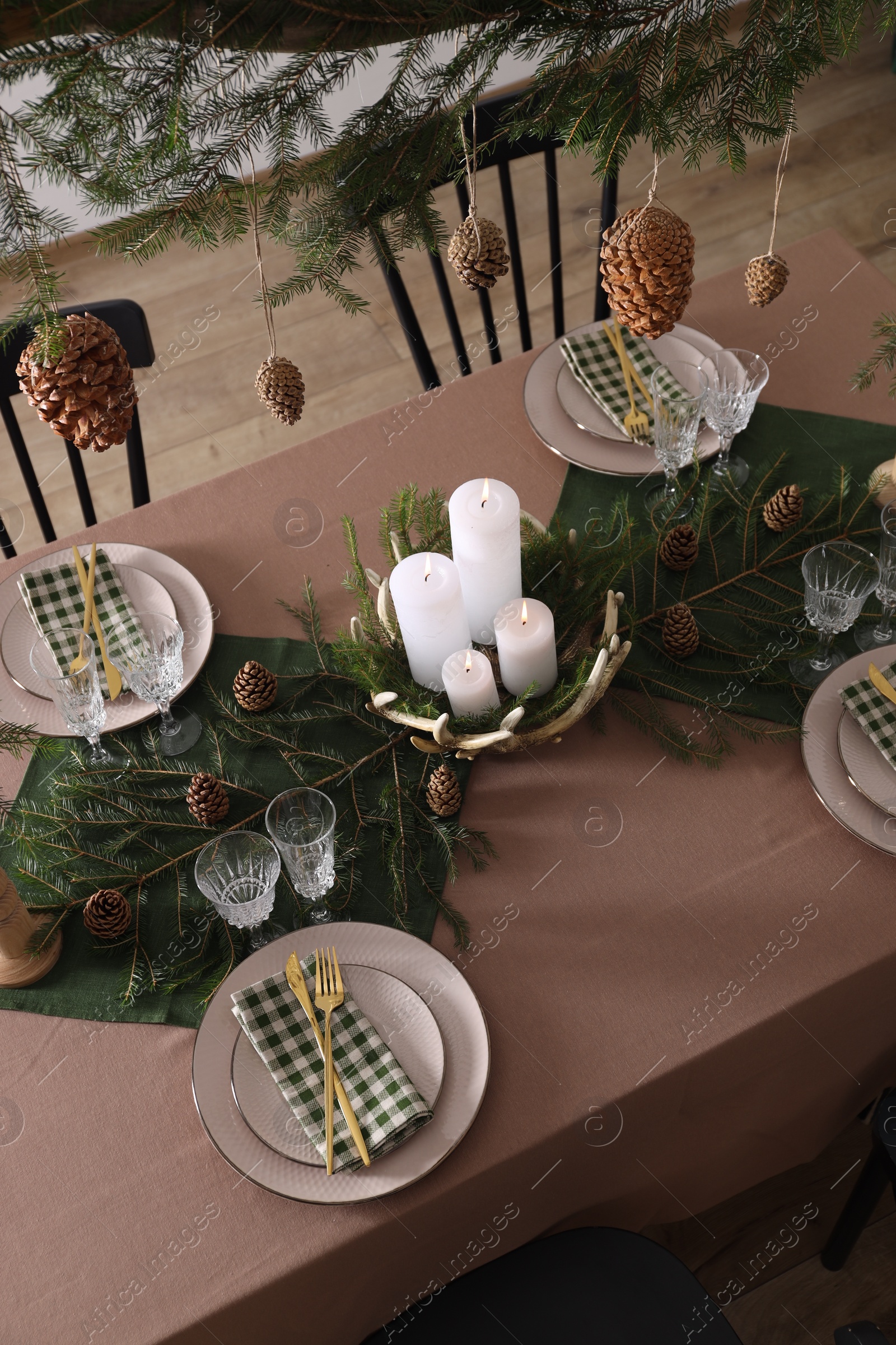 Photo of Christmas table setting with burning candles and other festive decor, above view