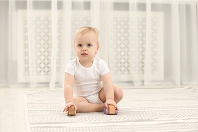 Children toys. Cute little boy playing with wooden cars on rug at home