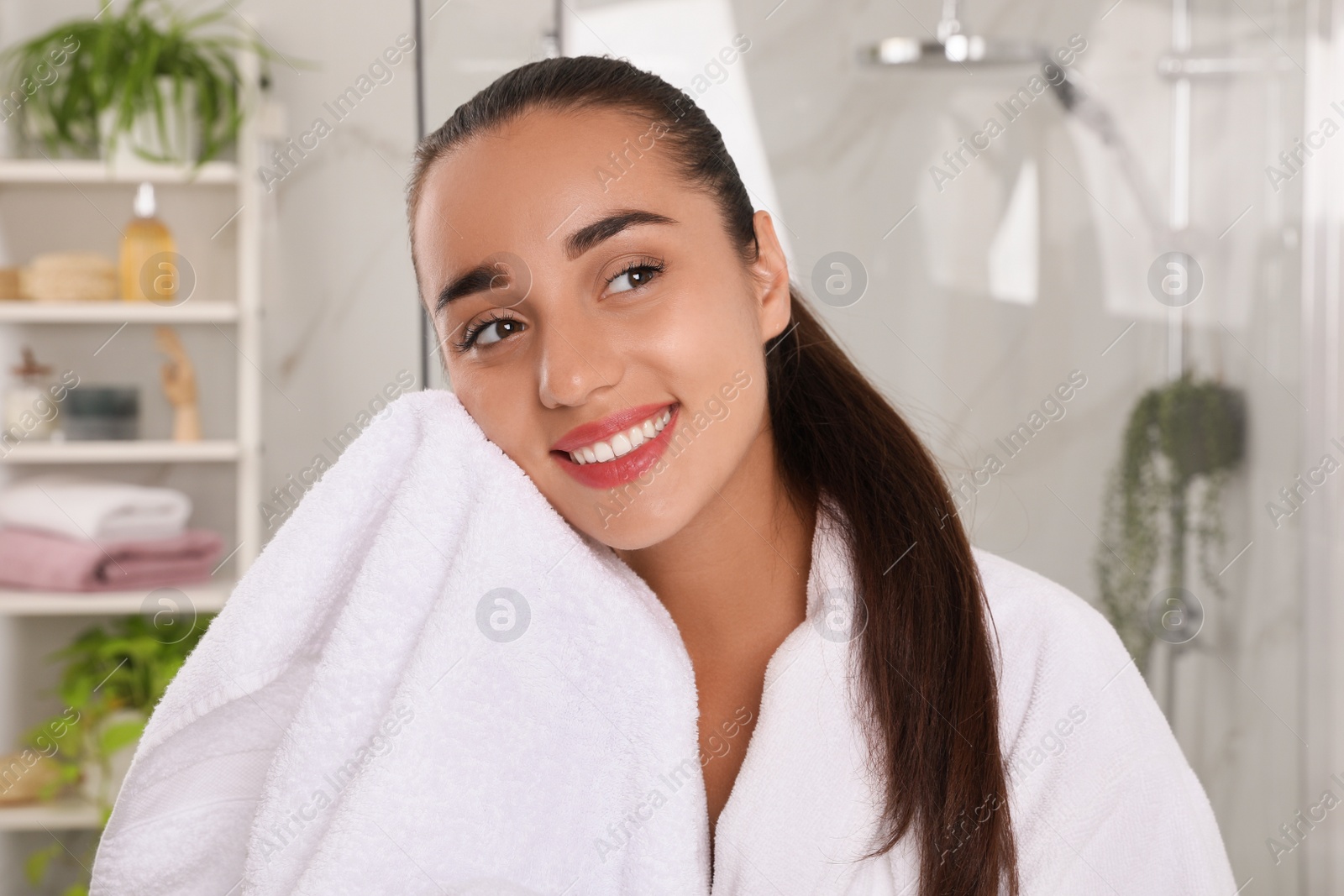 Photo of Beautiful young woman wiping face with towel in bathroom. Facial wash