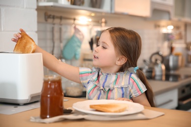 Photo of Little girl preparing toast for breakfast in kitchen