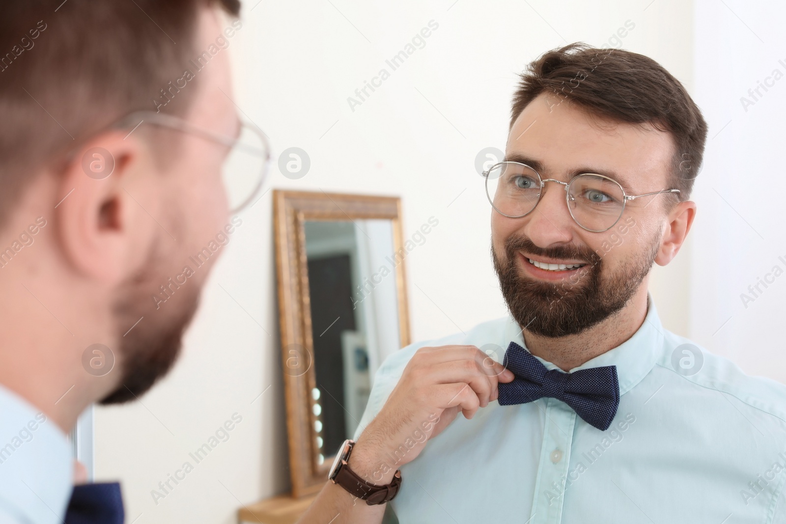 Photo of Young handsome man near mirror in makeup room