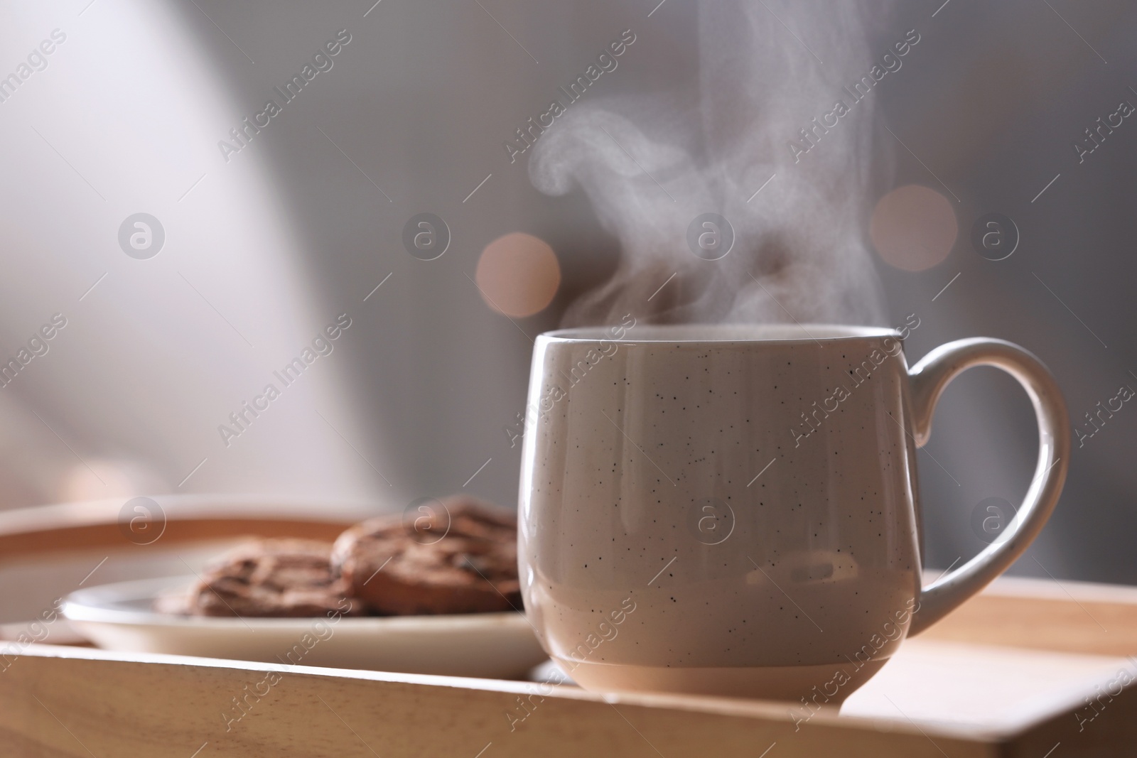 Photo of Cup of hot drink on wooden tray against blurred background, closeup