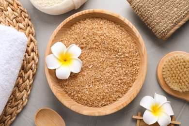 Salt and supplies for spa scrubbing procedure on grey stone background, flat lay