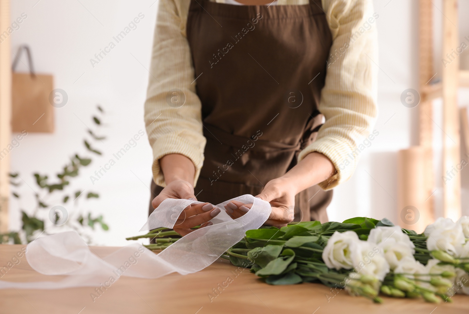 Photo of Florist making beautiful bouquet at table in workshop, closeup