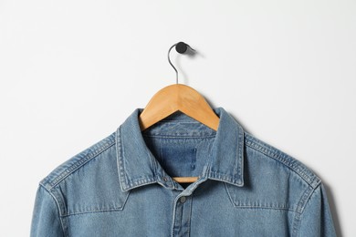 Hanger with denim shirt on white wall