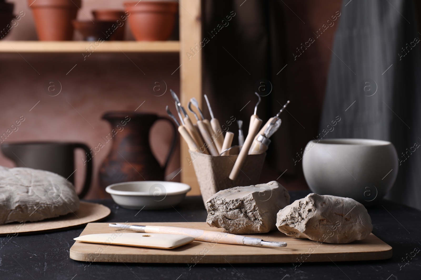 Photo of Clay and set of modeling tools on table in workshop