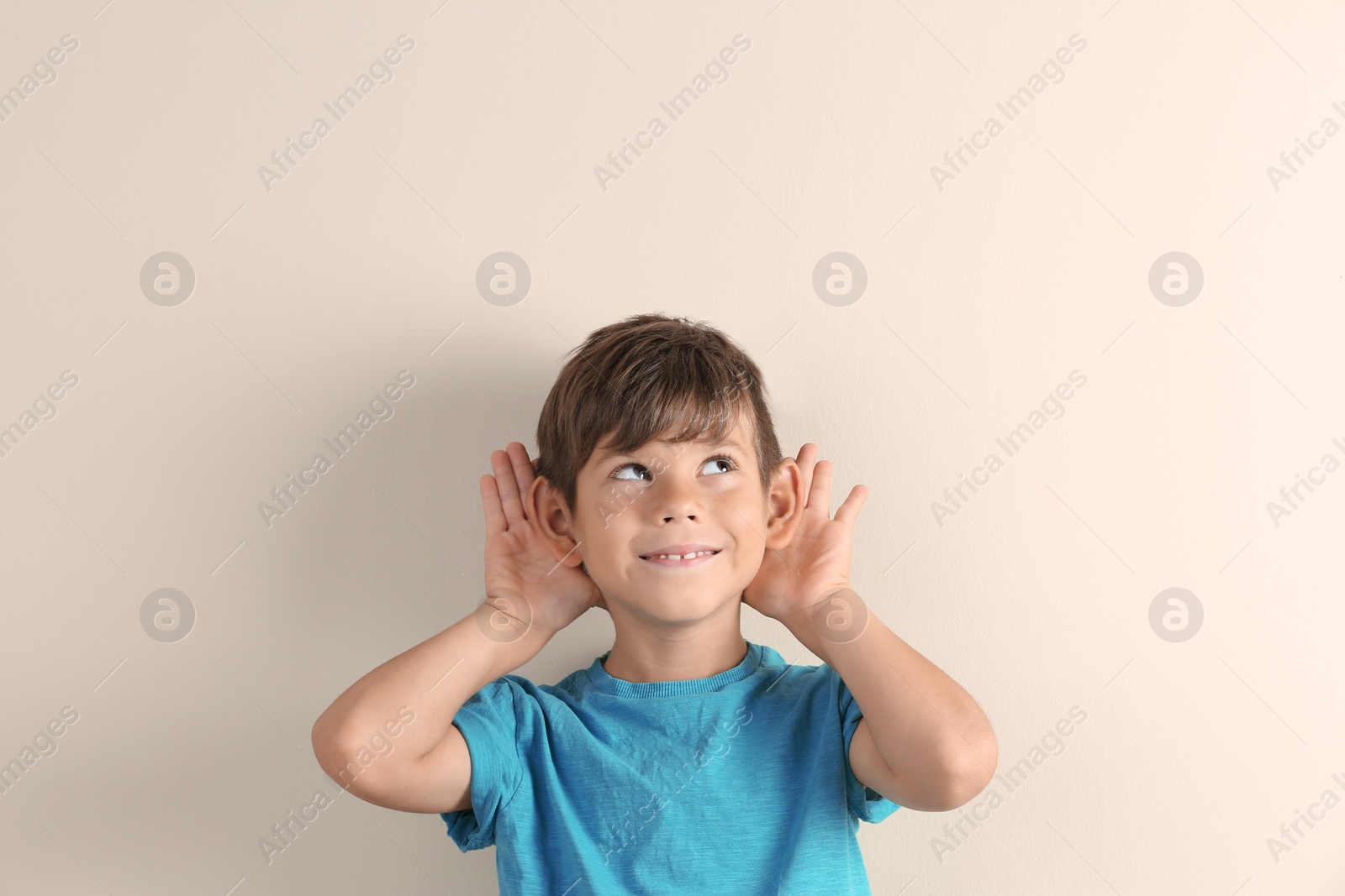 Photo of Cute little boy with hearing problem on light background