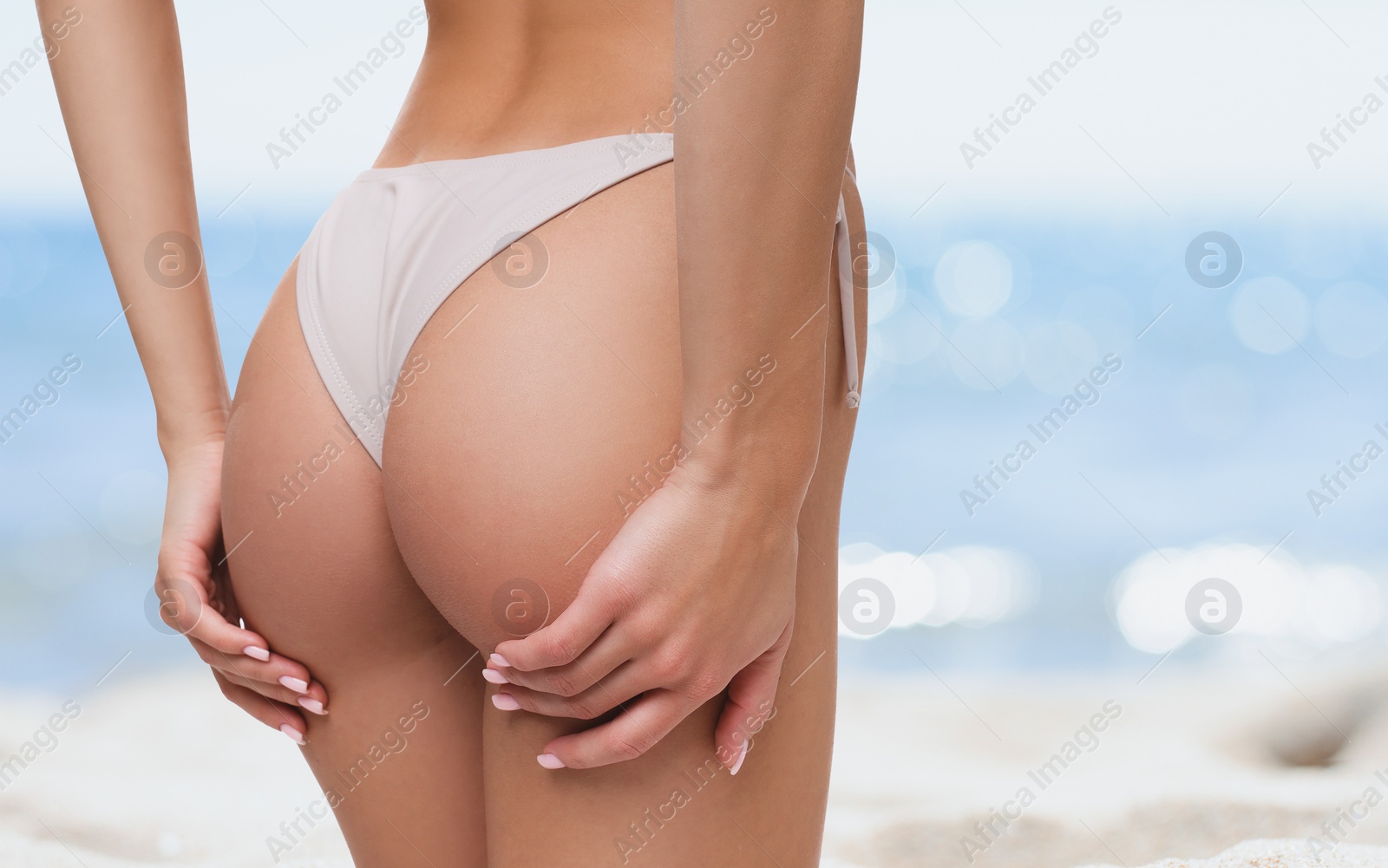 Image of Woman in stylish bikini on sandy beach near sea, closeup. Space for text