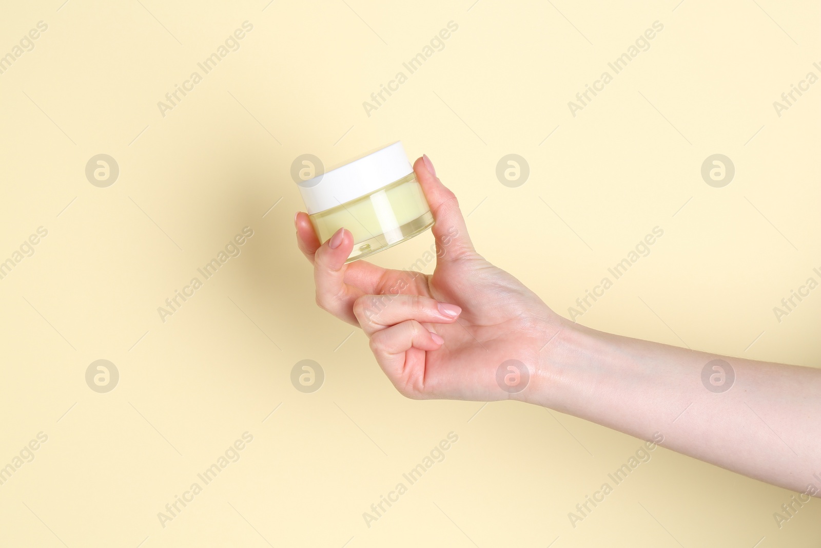 Photo of Woman holding jar of cream on yellow background, closeup. Space for text