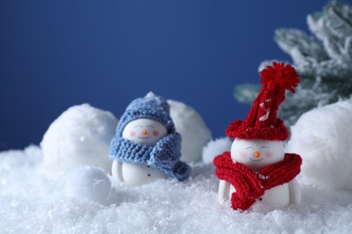 Cute decorative snowmen and fir tree on snow against blue background