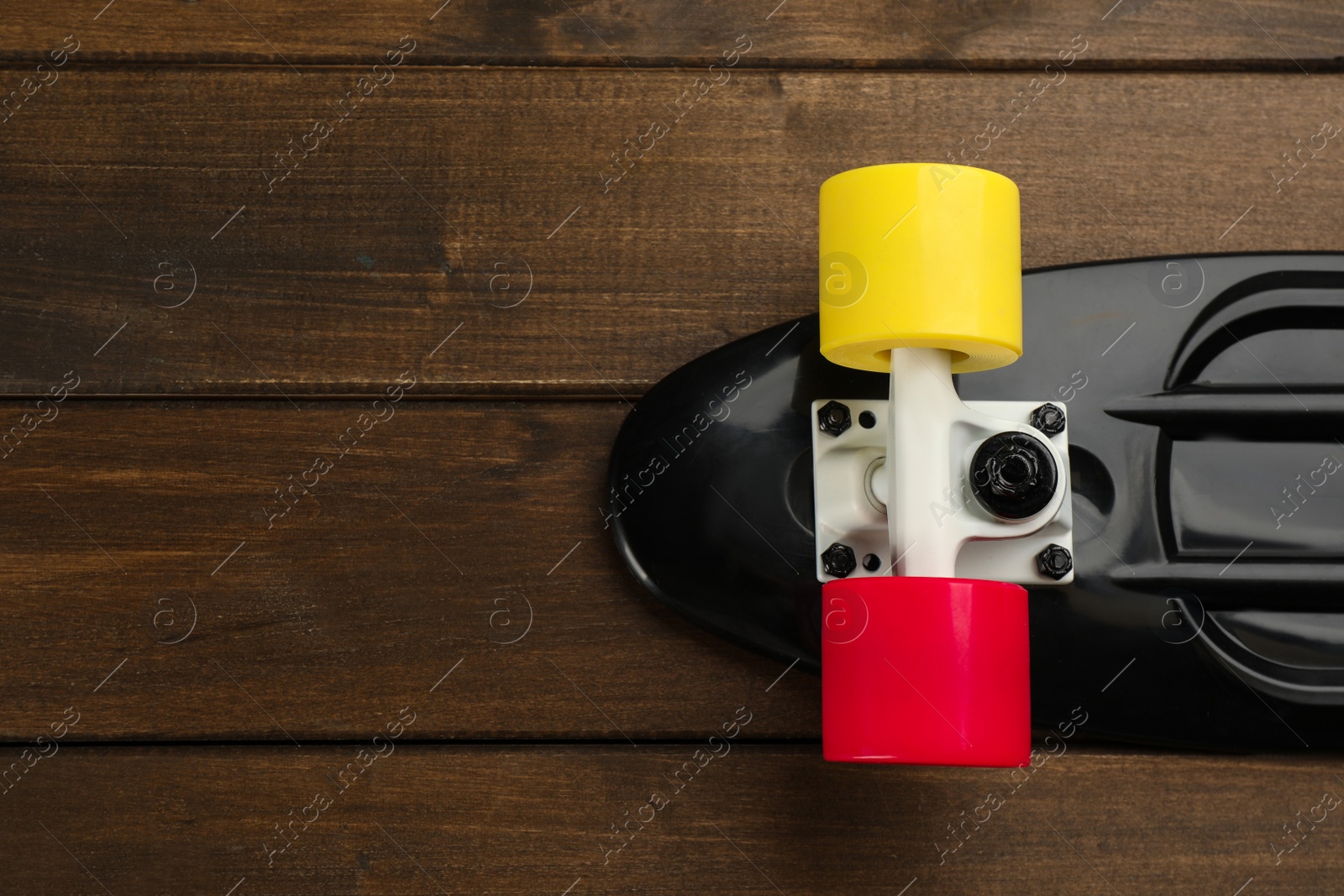 Photo of Black skateboard on wooden background, top view. Space for text