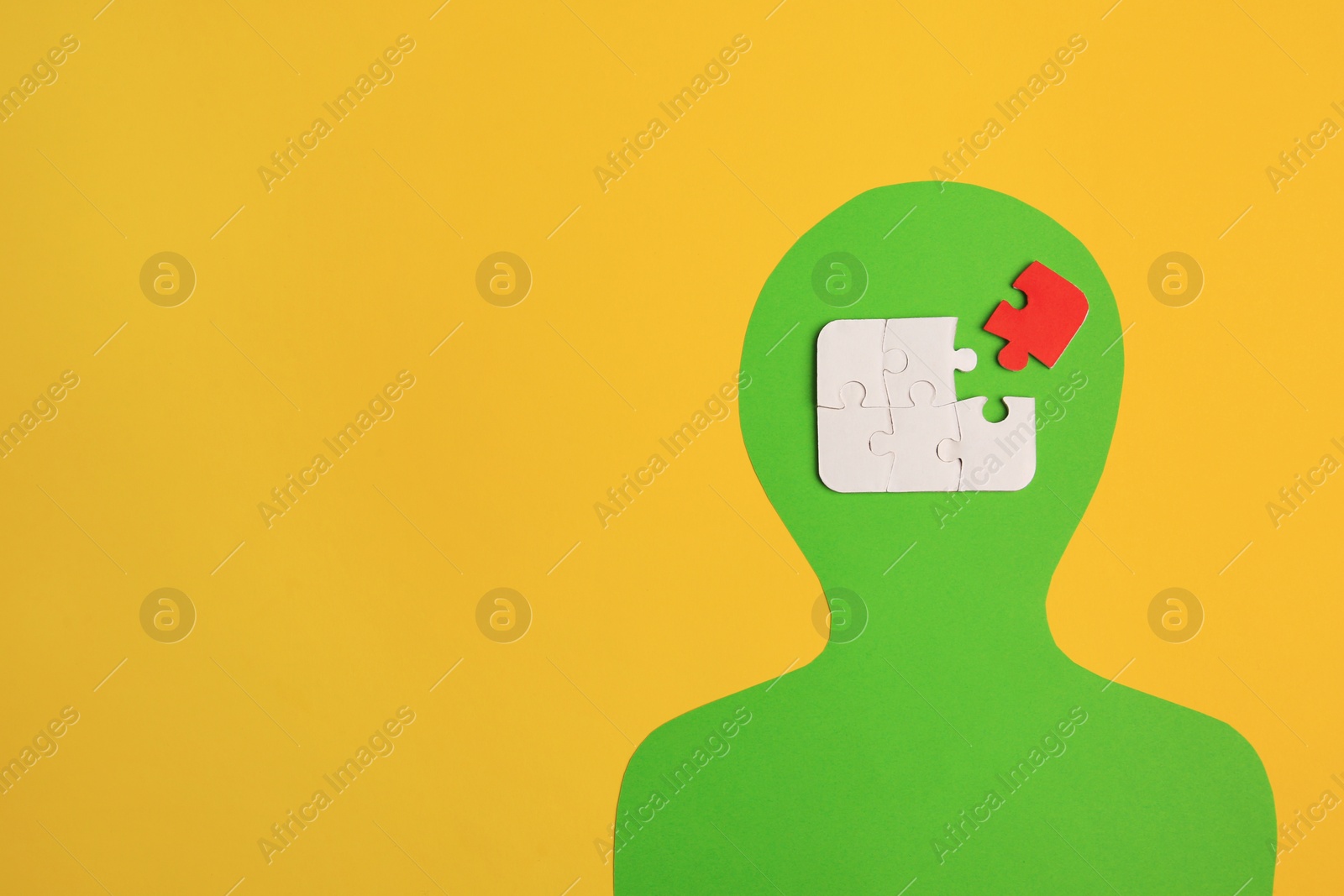 Photo of Human paper cutout with jigsaw puzzles in head, red piece as solution idea on yellow background, flat lay. Space for text