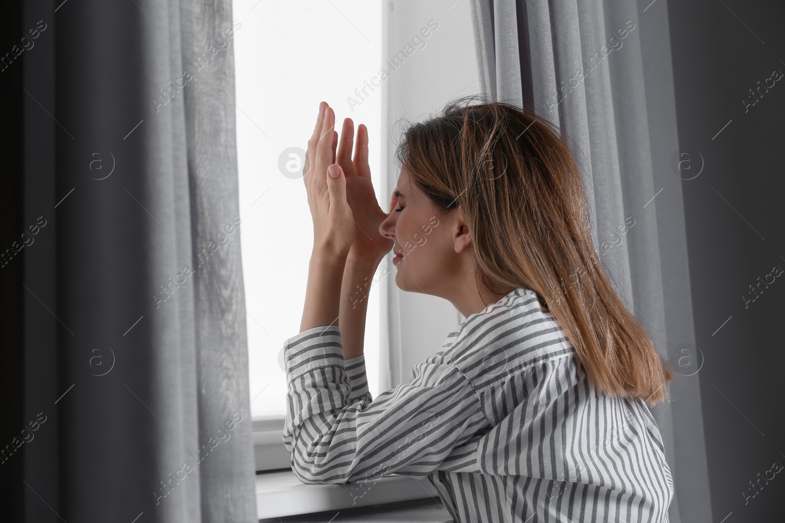 Photo of Lonely depressed woman near window at home